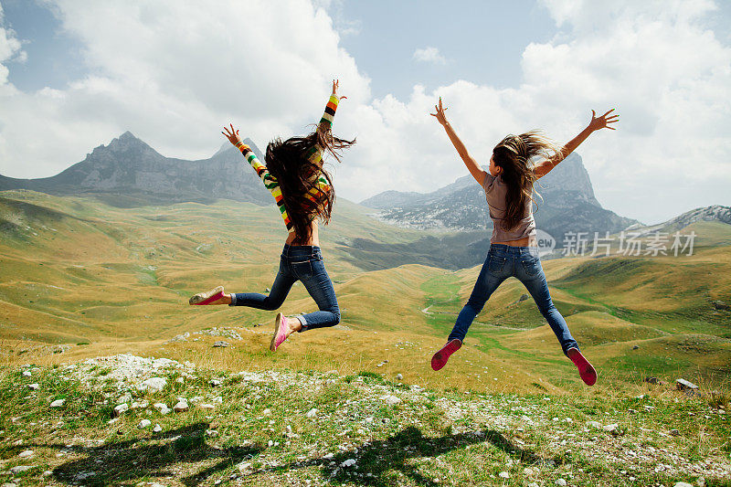 两个女孩快乐地在山上跳