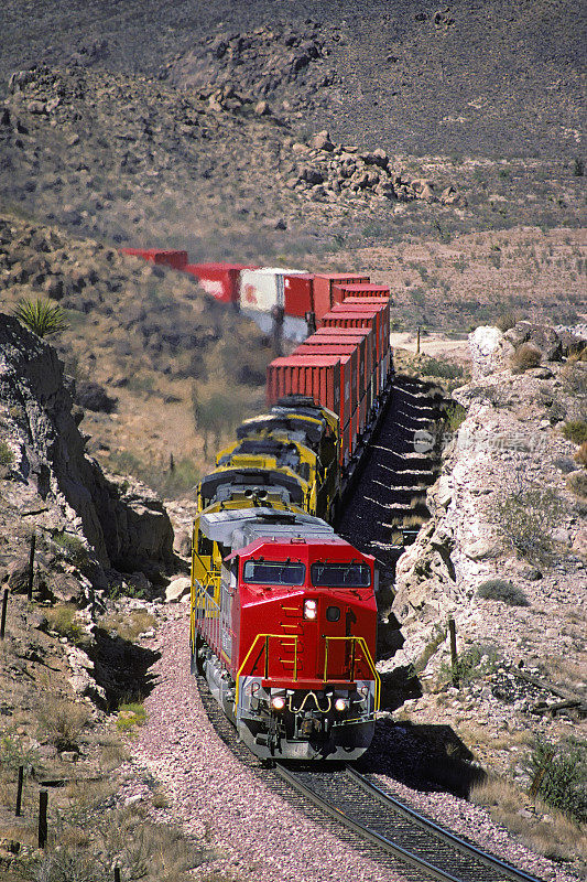 崎岖峡谷中的红色机车和集装箱火车