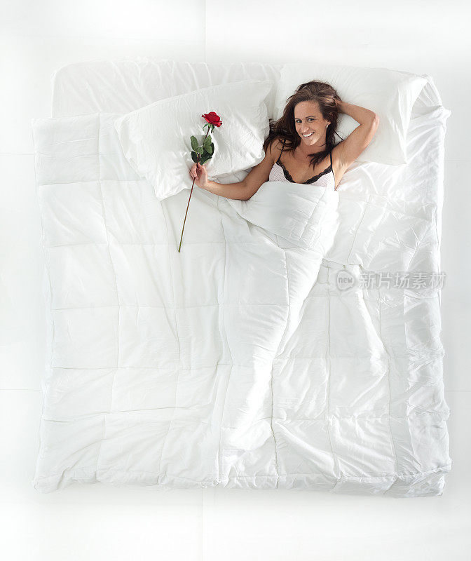 上图是一个女人躺在床上，抱着玫瑰
