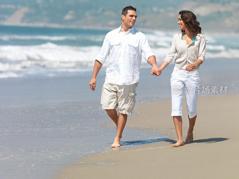 在海滩上牵手散步的夫妇