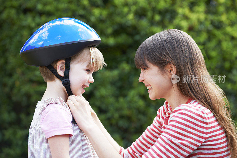 年轻女子给女孩戴上自行车头盔