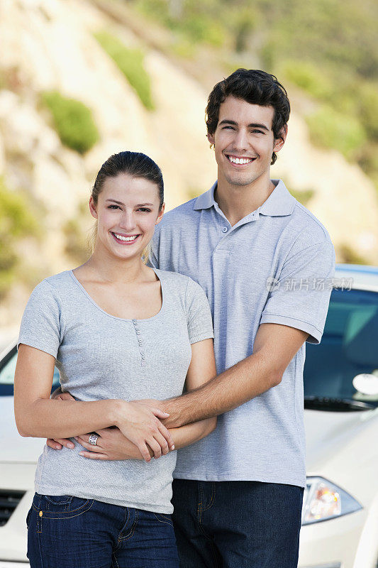 年轻夫妇在汽车旁摆姿势