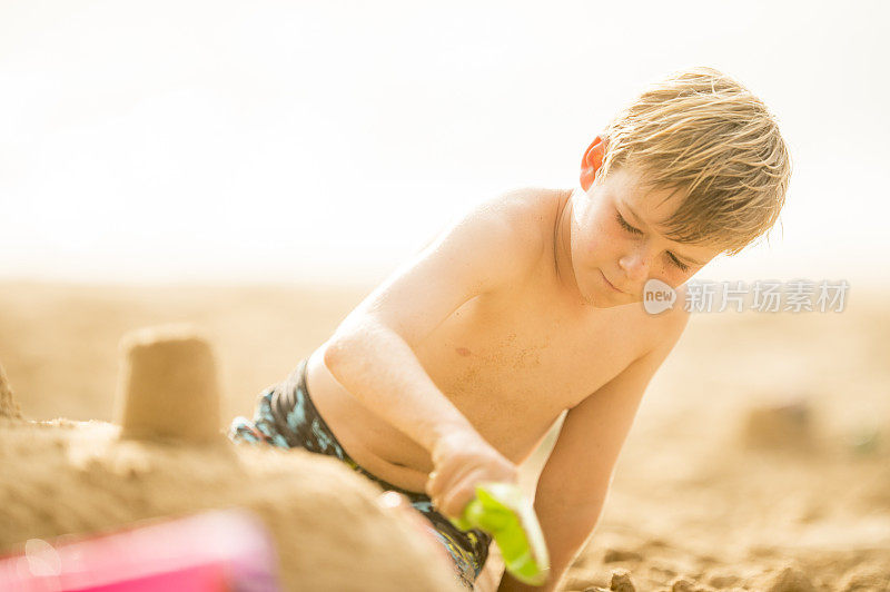 一个男孩在夏威夷的海滩上建沙堡