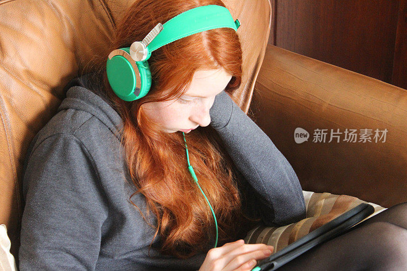 女孩戴着耳机在平板电脑上听音乐
