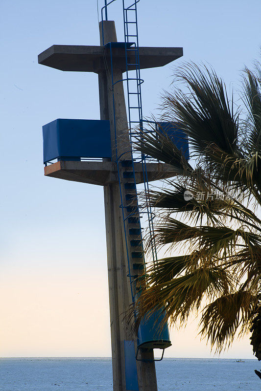 黄昏时的救生员瞭望塔、棕榈树和地中海。