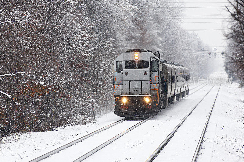 银色柴油机车推拉通勤列车在冬天的雪