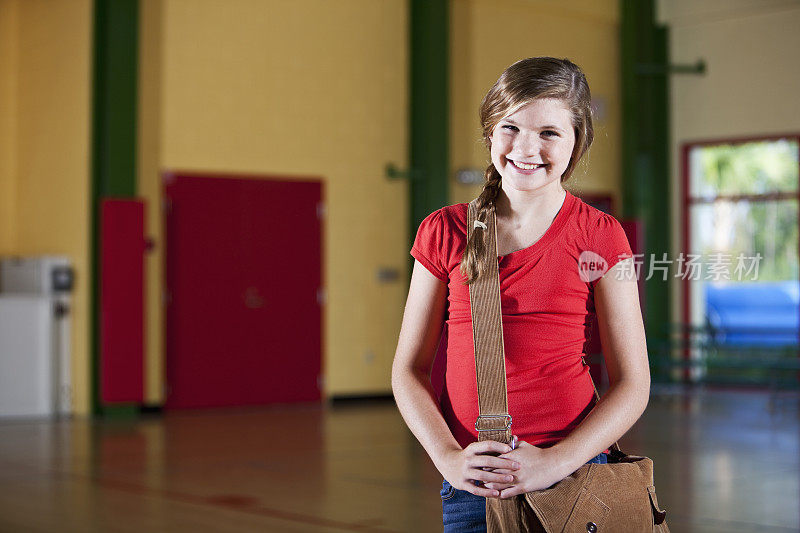 女孩拿着书包站在学校体育馆