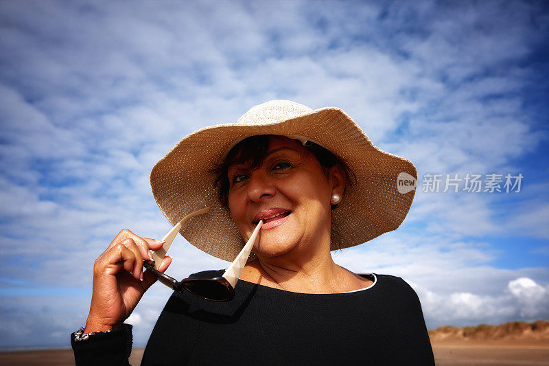 成熟微笑的西班牙妇女太阳镜和太阳帽