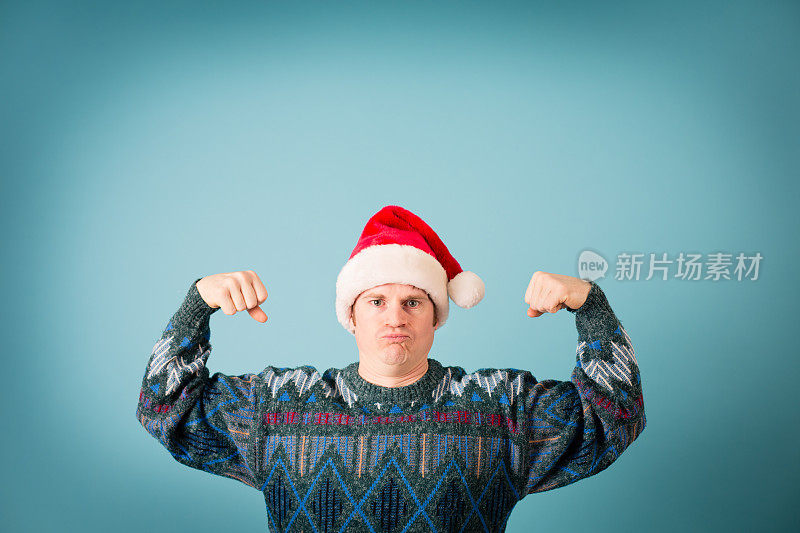 戴着圣诞帽和丑陋毛衣的男人展示肌肉