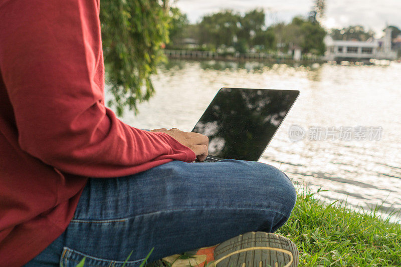 作者在公园湖边用笔记本电脑工作