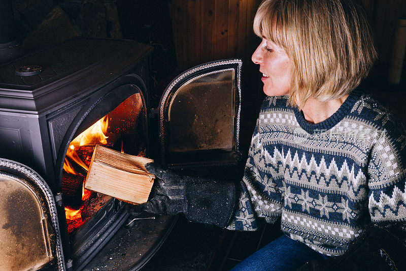 女人把木头放进烧木头的炉子里
