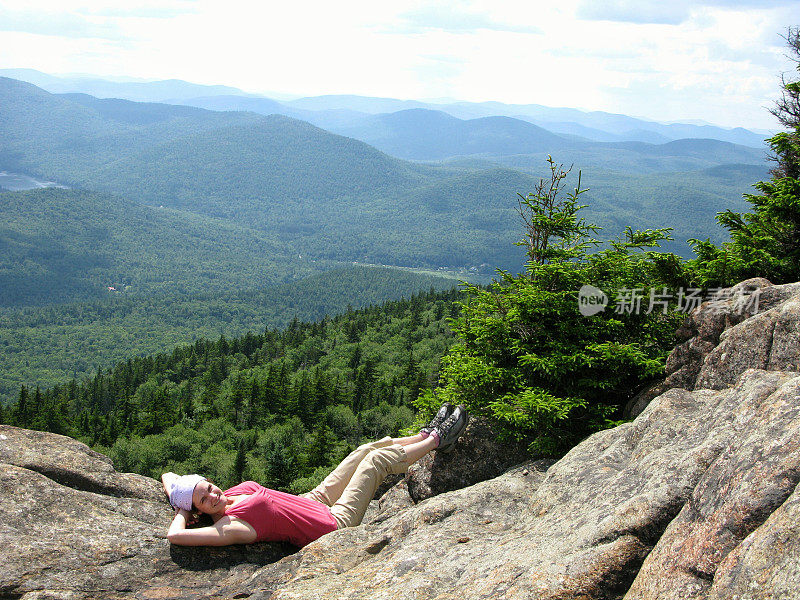 女性自然爱好者阿迪朗达克山徒步旅行者休息在岩架上