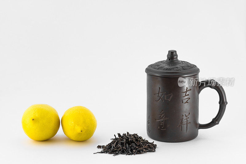 两个柠檬，中国杯和干茶孤立在白色的背景