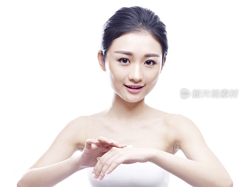 年轻的亚洲女子将乳液涂在手上