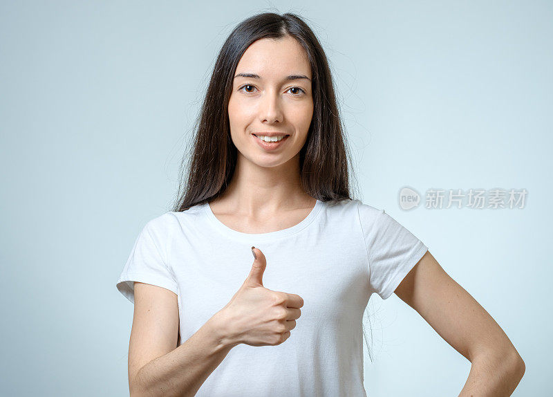 微笑快乐年轻的黑发女人显示拇指向上的手势孤立在白色的背景