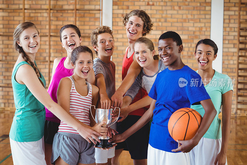 高中的孩子们在篮球场上拿着奖杯微笑着