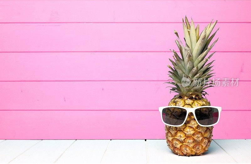 时髦的菠萝配太阳镜，衬着粉红色的木头