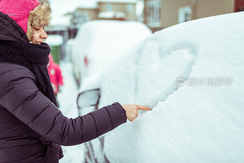 妻子在丈夫被雪覆盖的车上画了一个心形