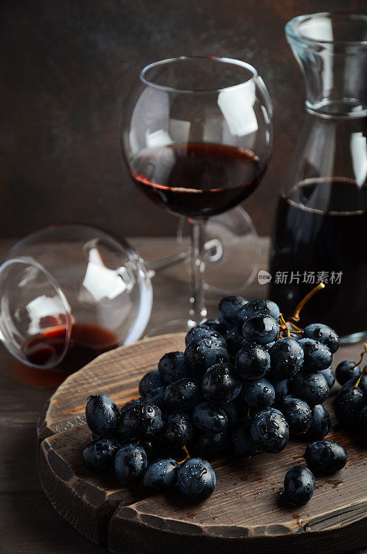 木桌上的新鲜黑葡萄和红酒