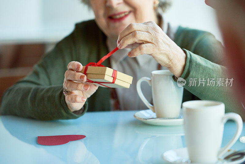 积极的资深女性在咖啡馆拆礼物