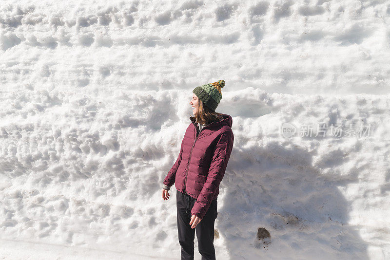 一个年轻的女人站在一个巨大的雪堆前