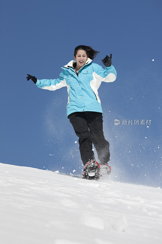 年轻女子在雪地鞋上奔跑