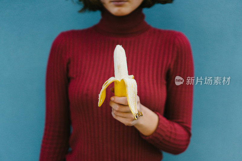 穿红色高领毛衣的女人，蓝色背景是香蕉