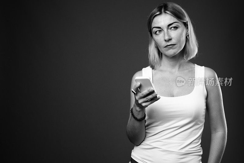摄影工作室拍摄的成熟的短发女性用手机拍摄的黑白照片