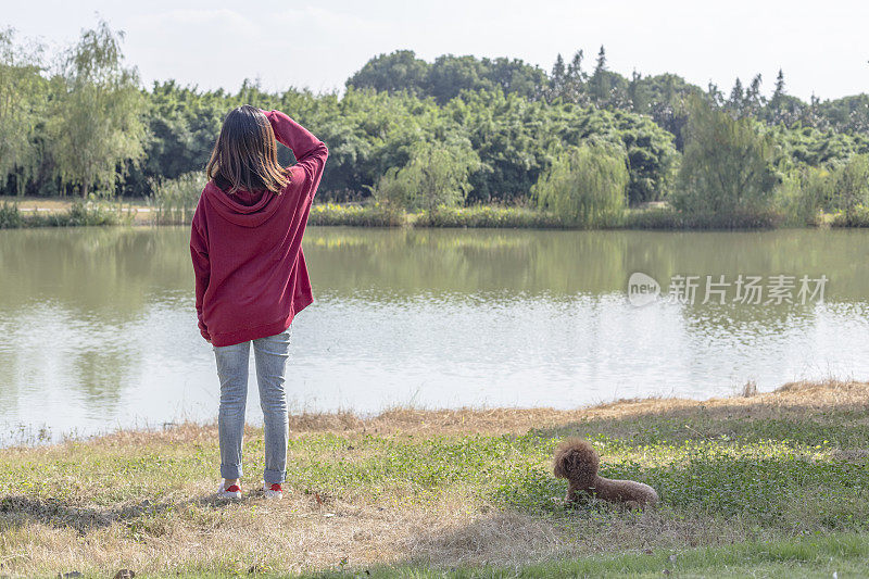 一个女人和她的小狗在湖边玩耍