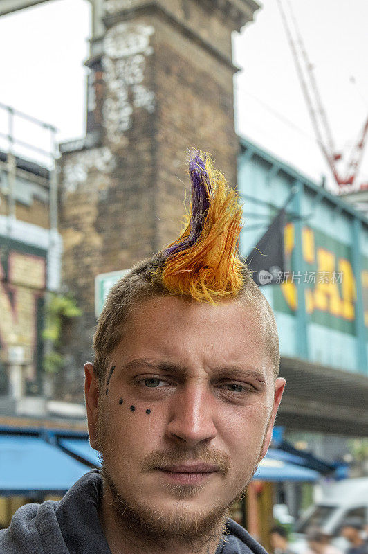 伦敦朋克现场，一个朋克男性与冠状发型，在后面的卡姆登锁标志在卡姆登市场的入口。