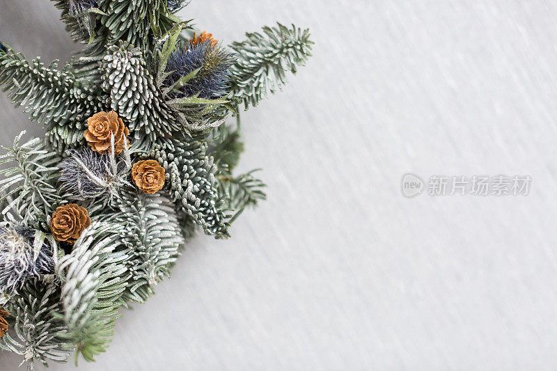 冬季，装饰，设计理念。在白雪皑皑的背景下，是针叶树的新鲜树枝，上面长着小小的木质玫瑰，松果，上面覆盖着细小的冰粒
