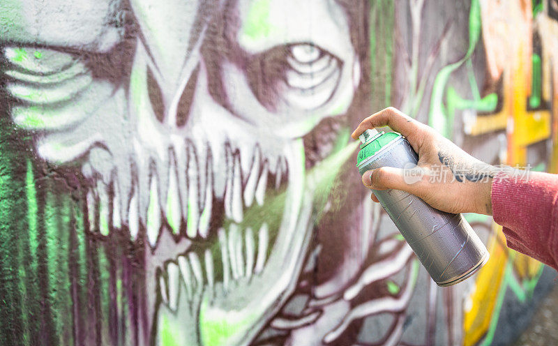 街头艺术家在公共墙上画彩色的怪物涂鸦-现代艺术概念与城市人表演和准备活壁画与多色气溶胶喷雾-集中在手上