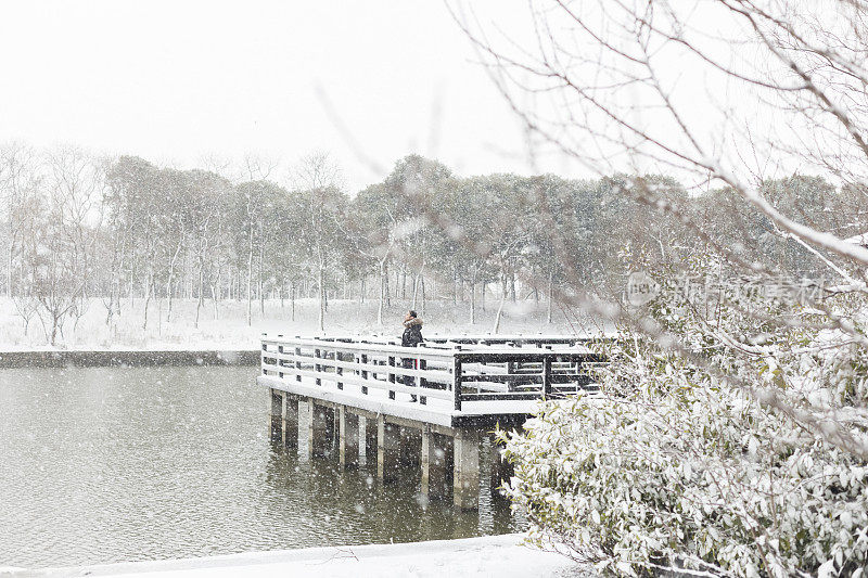 一个女人站在白雪覆盖的木桥上的宁静景象