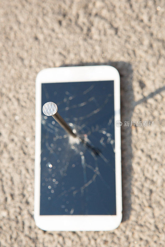 金属钉子和智能手机和一个破碎的屏幕在石头表面。力量的概念。