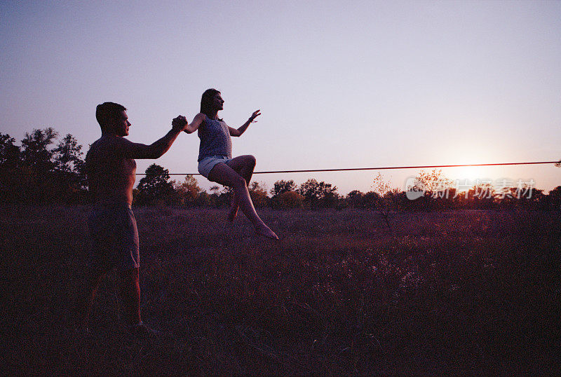 日落时分，一名女子在草地上的绳索上跳跃。