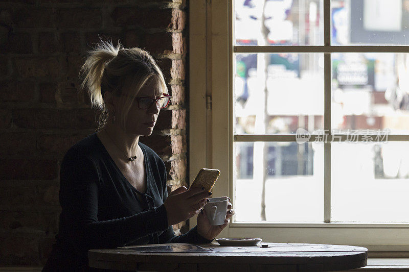 一个女人坐在餐厅里喝着咖啡，看着电话留言