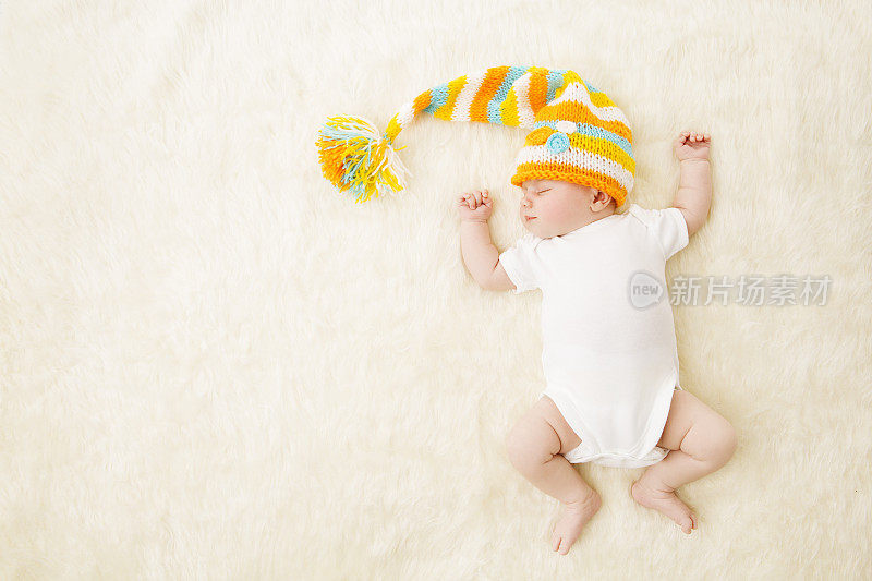 婴儿睡彩色帽子，新生儿在紧身衣睡在地毯的背景