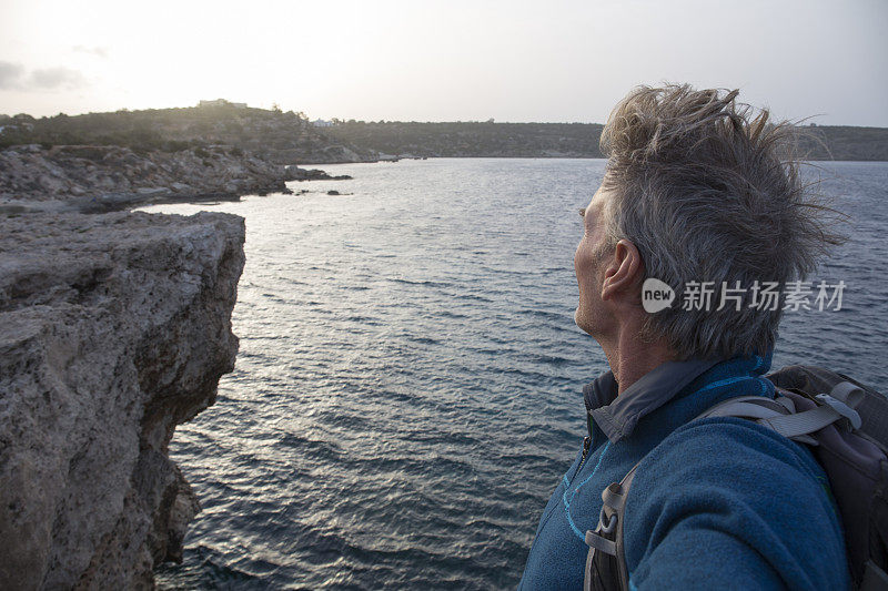 日出时分，一名男性徒步旅行者望向大海