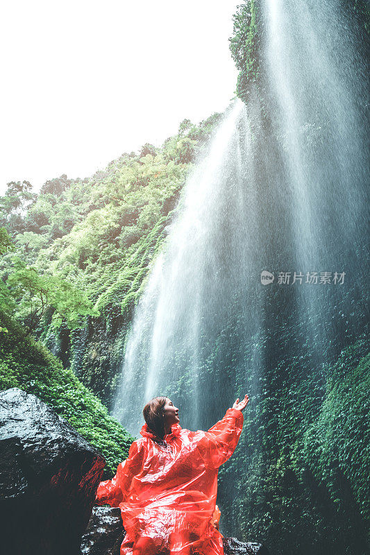 旅游女人冒险和站在Madakaripura瀑布放松，东爪哇岛，印度尼西亚