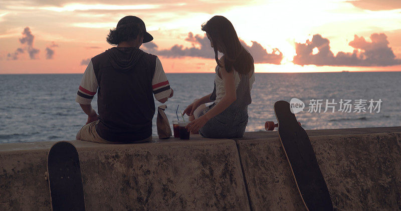 一对年轻的滑冰夫妇边看日落边聊天。