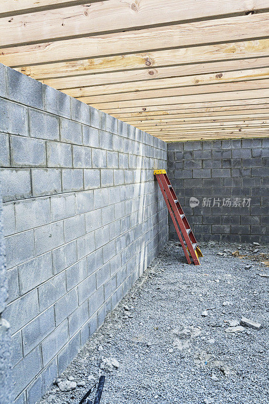 建筑梯子靠在新地下室混凝土砌块墙上