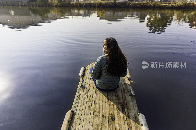 少女坐在湖边的码头上