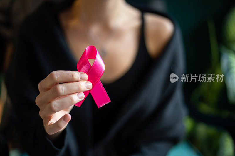 手持粉色乳腺癌宣传丝带的妇女