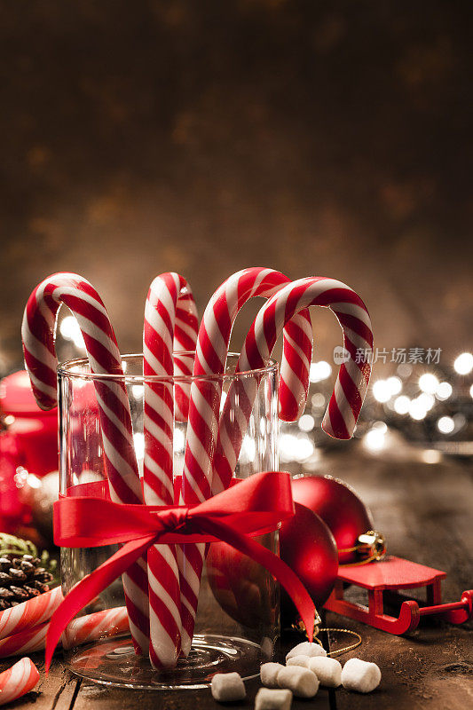 圣诞背景:木桌上的玻璃杯里的拐杖糖