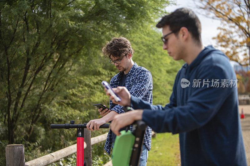 两个年轻的男性朋友用智能手机在网上预订和支付租用的电动滑板车