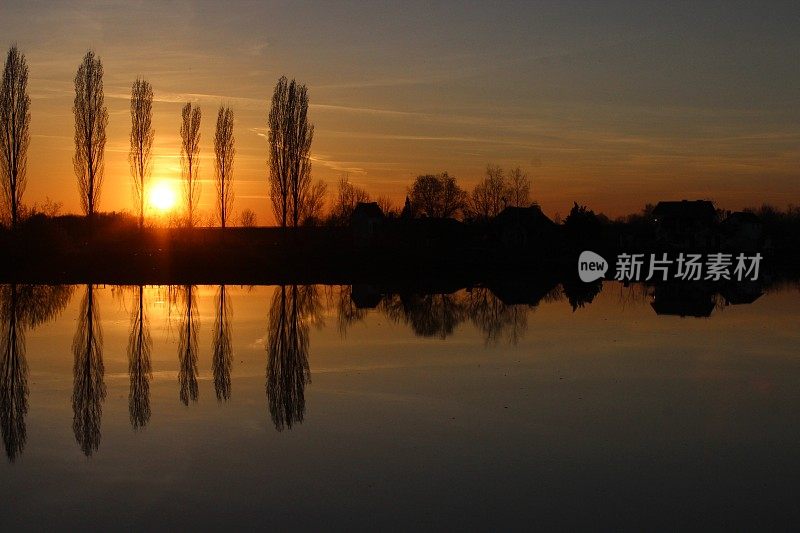 夕阳西下，树木倒映在湖面上