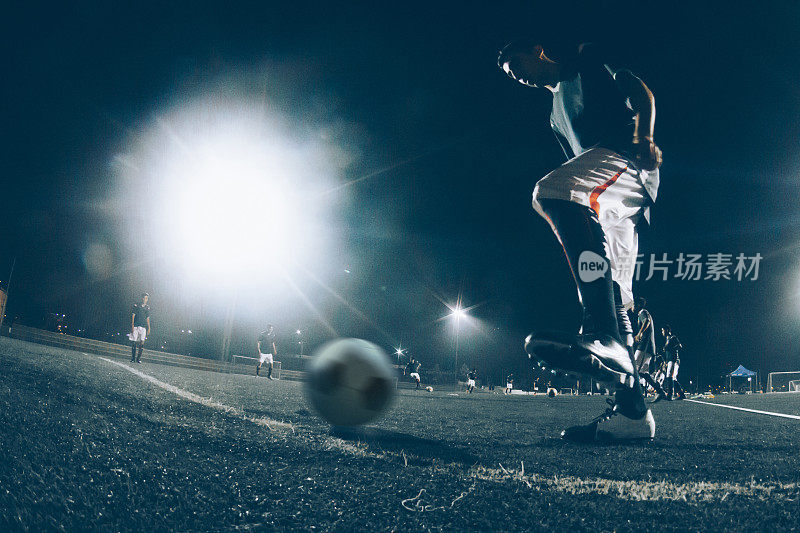 一群职业足球运动员在比赛前在夜间体育场练习