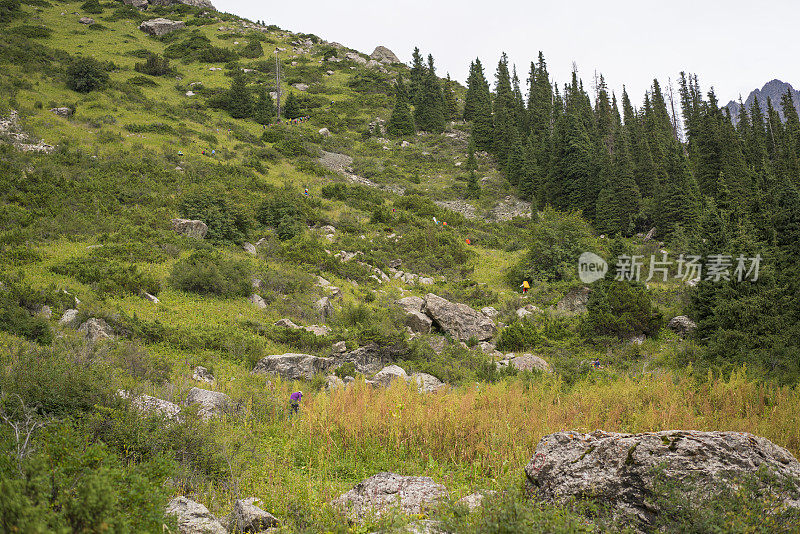 吉尔吉斯斯坦的卡拉科尔山，许多游客在通往阿拉库尔湖的山坡上徒步旅行