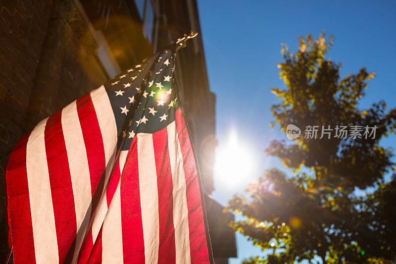 美国国旗在阳光明媚的背景下挂在墙上