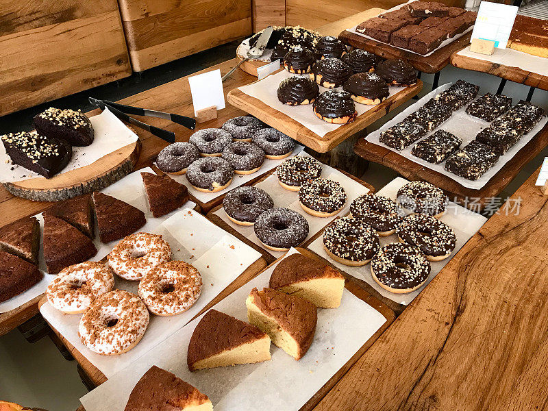 甜点与甜甜圈、小圆面包、布朗尼、木质蛋糕一起陈列于咖啡厅